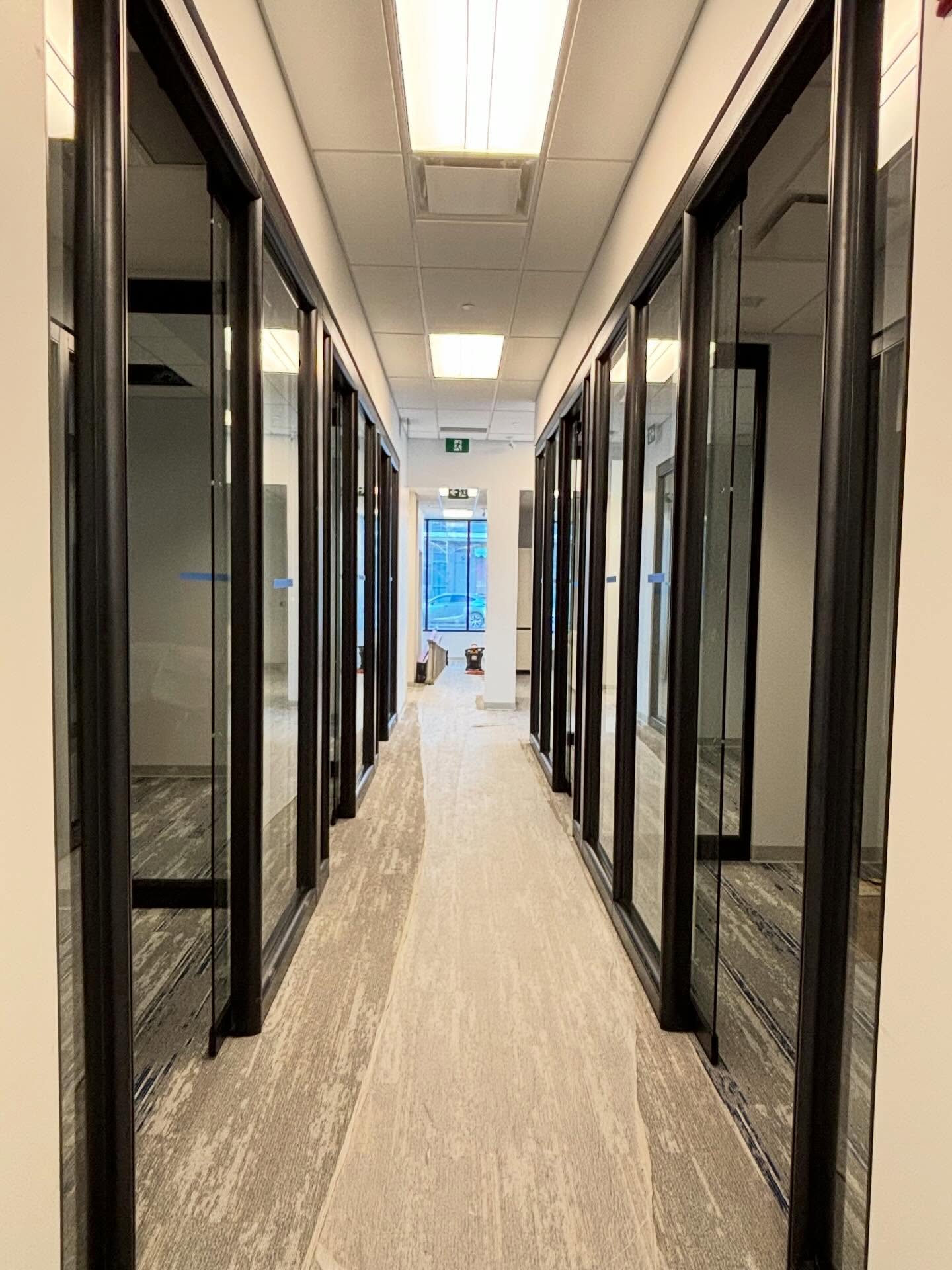 Corridor lined with black-framed glass office fronts
